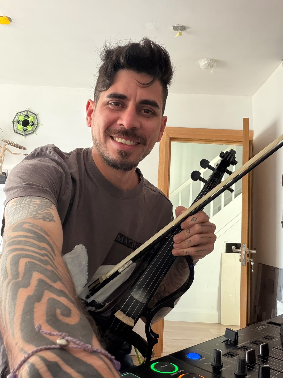 Eduardo Briglia smiling at DJ decks with violin